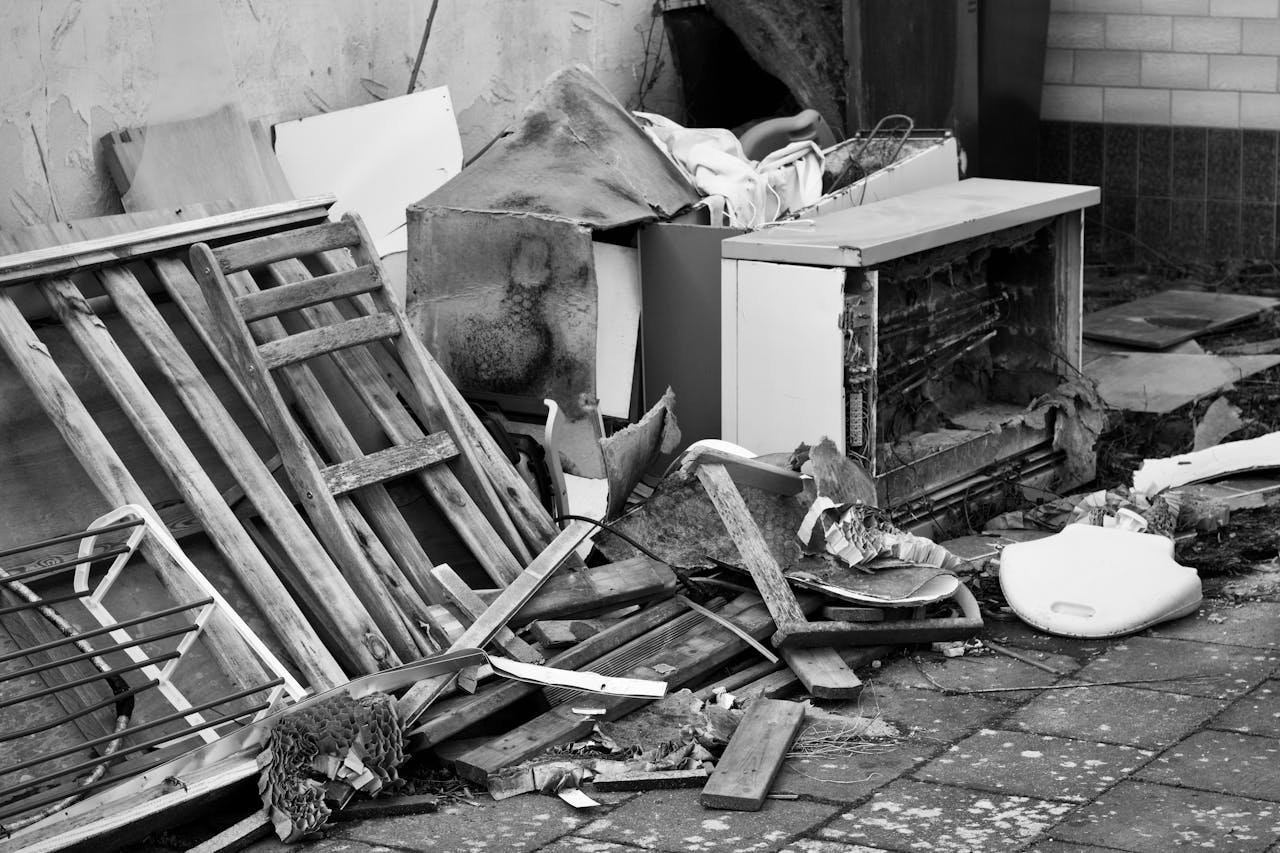 Black and white image of a pile of discarded objects in an urban setting, highlighting decay.